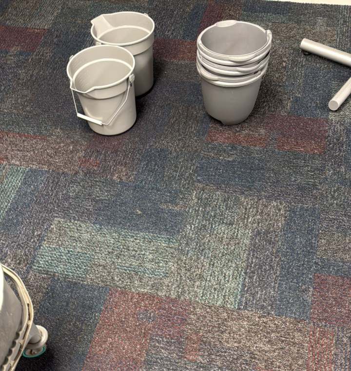 Catch buckets set out on commercial carpet under a roof leak