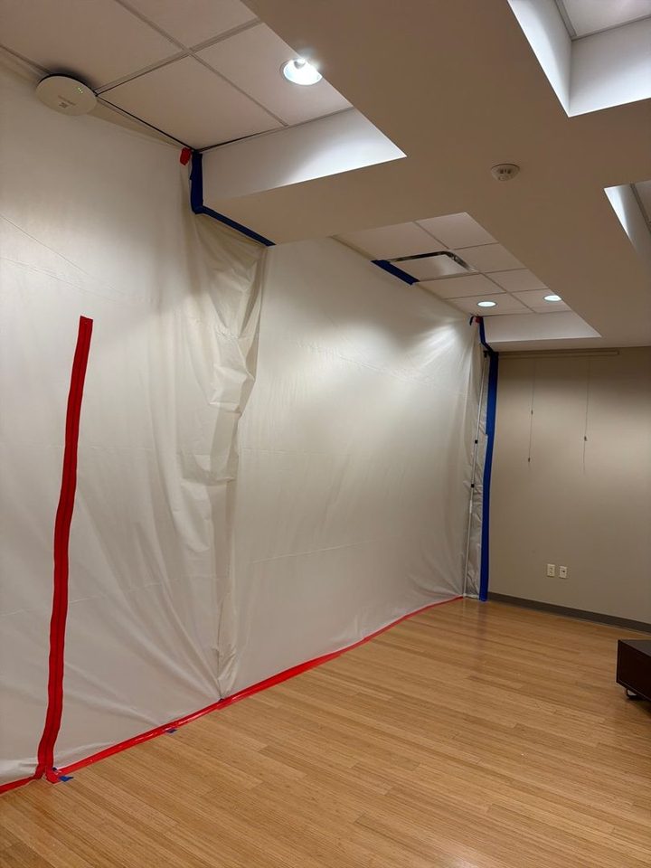 Plastic containment wall with a zipper door, sealed to the drop ceiling of a commercial space during a water loss