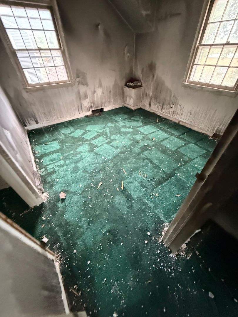 Soot drips running down a bedroom wall between two windows after a fire