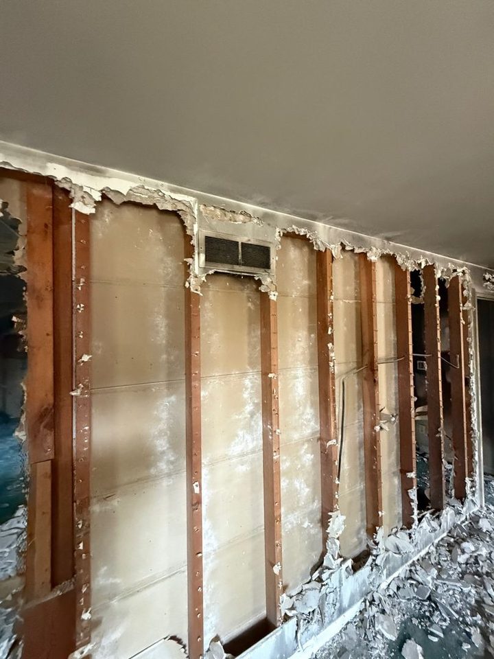 Wall with damaged drywall cut away to bare studs after a fire
