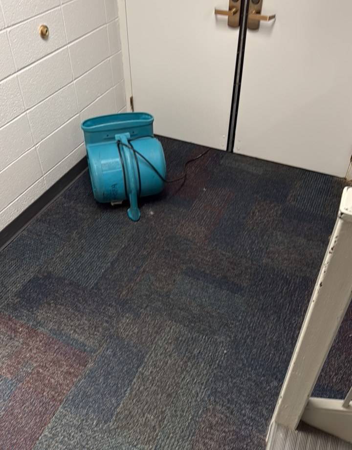 Air mover drying a carpeted stair landing on a water damage job